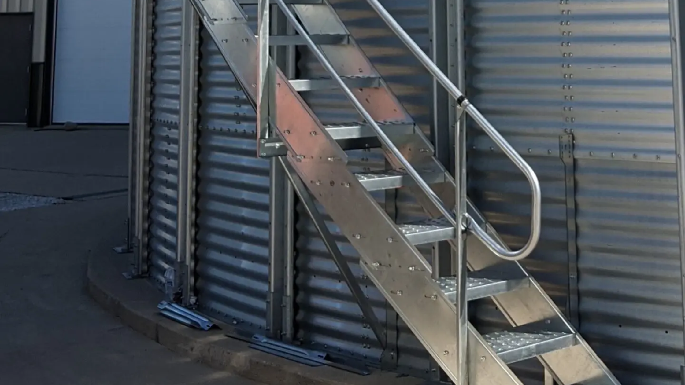 Close-up of farm duty sidewall stair stringers bolted to the corrugated sidewall sheets of a grain bin