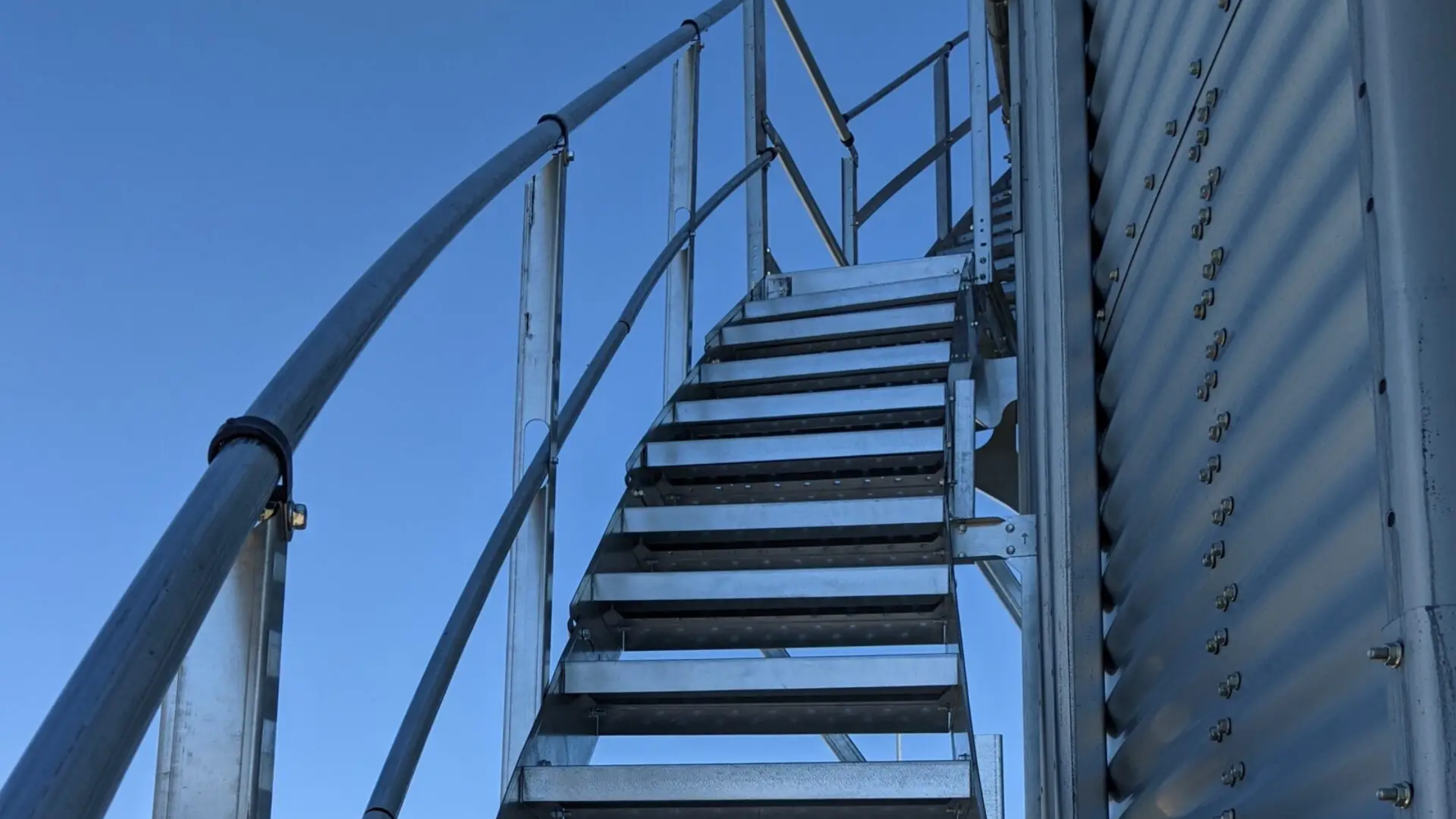 Looking up a run of galvanized grain bin stairs with anti-slip treads and double handrails